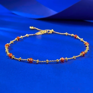 Detail showing the gold beaded chain with red multifaceted gemstones and floral charms