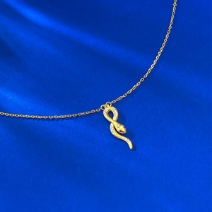 Collier avec pendentif serpent doré élégant serti de zircons et yeux rouges sur velours bleu