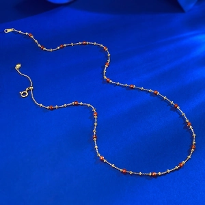 Detailed macro of gold beaded chain with red gemstones and adjustable lobster clasp