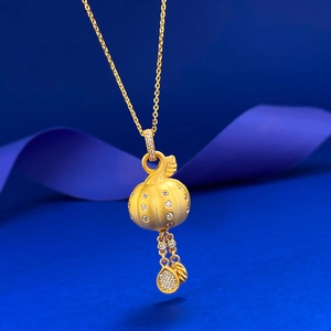 Détail macro du pendentif sac de fortune en or brossé avec zircon blanc et pompon sur bleu