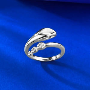 Macro shot of silver bypass ring with three round zircons on blue silk background