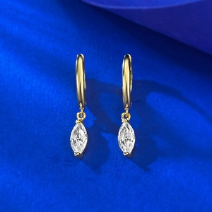 Macro d'oreillettes avec cristal marquise doré posées sur un support en velours bleu