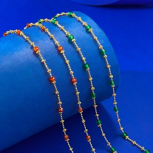 Detailed macro view of S925 silver beaded necklace with green and orange faceted gems