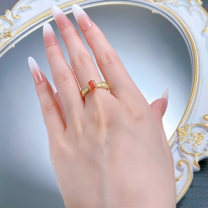 Dettaglio anello in argento S925 con gemma arancione ovale e finitura oro sul dito