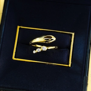Detailed macro view of a gold-plated snake-shaped ring with three sparkling zircons in a box
