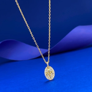 Gros plan du pendentif fleur de lys doré serti de cristaux sur fond de soie bleu foncé