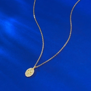 Collier avec pendentif fleur de lys doré et zircons sur un fond bleu élégant
