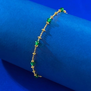 Macro shot of S925 silver gold-plated ball chain with faceted green crystal beads