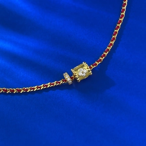 Bracciale a treccia rossa e catena dorata con perla quadrifoglio su velluto blu
