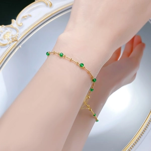 Detail of adjustable gold chain bracelet with emerald green beads on female wrist