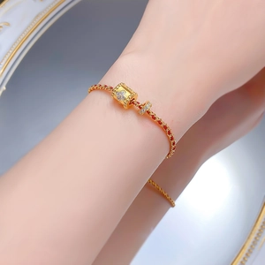 Dettaglio del bracciale in corda rossa con perla a quadrifoglio dorata e zirconi