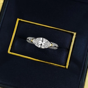 Vue macro d'une bague diamant marquise dans son écrin de velours bleu et métal bicolore