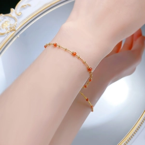 Macro view of dainty gold-plated S925 silver bracelet with orange gemstone beads