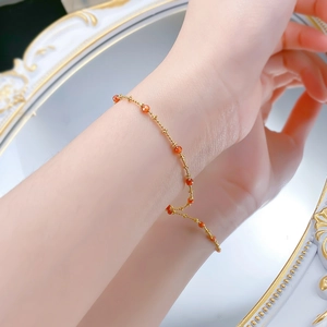 Elegant gold bead chain bracelet with red carnelian stones worn by a model