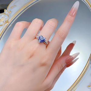 Close-up of heart-shaped blue sapphire ring on hand with elegant mirror reflection