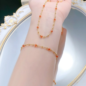 Detail of a 18K gold chain bracelet with red carnelian beads on a woman's wrist