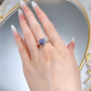 Detail of a heart-cut tanzanite blue sapphire ring on a model hand with mirror reflection
