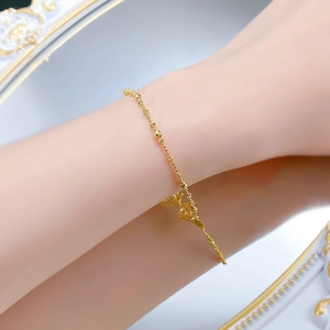 Detailed macro view of an elegant gold bead chain bracelet with a round branded pendant tag