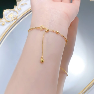 Detail of gold bead chain bracelet with heart pendant and spring clasp closure