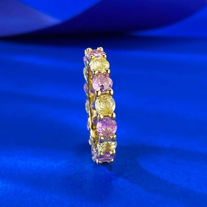 Détail macro d'une bague éternité en or avec gemmes rondes jaunes et roses alternées