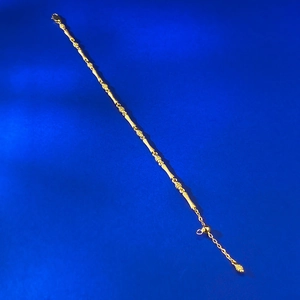Close-up of golden bamboo link bracelet with floral charms and adjustable clasp