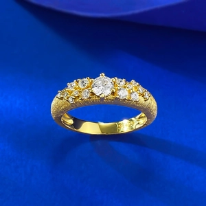 Macro shot of gold plated textured ring band with clustered zircon stones on blue background