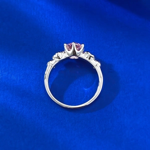 Detailed side view of the silver ring with pink gemstone and ornate carved patterns