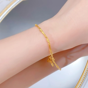 Detailed shot of a gold bamboo-style S925 silver bracelet with a small lucky bag charm