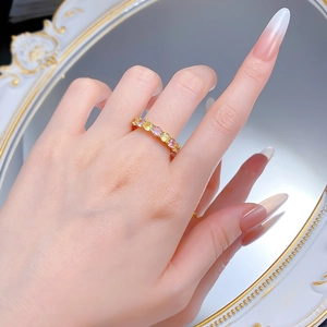 Vue détaillée d'une bague dorée sertie de gemmes jaunes et roses sur la main d'un mannequin