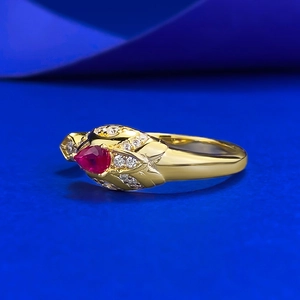Detailed side view of vintage gold ring featuring a pear-cut ruby and leaf motifs