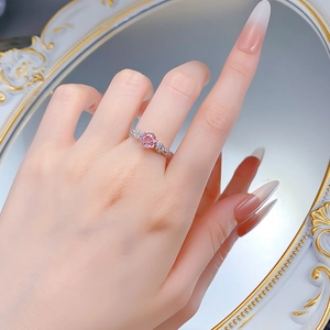 Close-up of a pink sapphire ring featuring a rose-shaped silver band on a hand