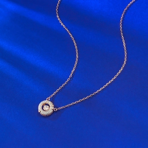 Elegante collana in oro rosa con ciondolo rotondo scintillante su sfondo blu scuro