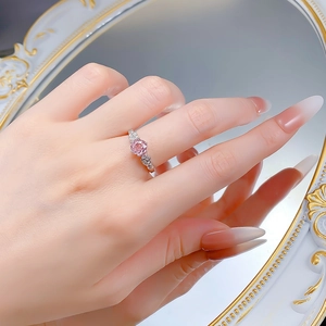 Macro shot of silver ring with pink sapphire and detailed rose accents worn on finger