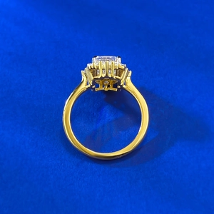 Macro view of a rectangular emerald-cut white gem with gold halo setting and pavé accents