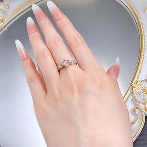 Detail of rose gold ring with pink round gemstone and carved rose petals on the band