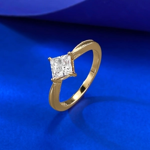 Gold princess cut cubic zirconia ring with milgrain details on a blue background