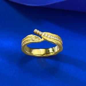 Macro detail of golden feather ring with brushed texture and tiny inlaid diamonds