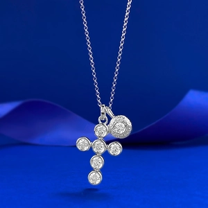 Vue macro d'un collier croix en argent orné de gemmes rondes sur fond bleu élégant