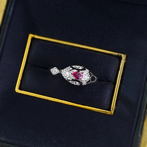Detail of S925 silver ring featuring a heart-cut red gemstone and white pave accents