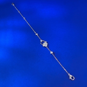 Macro shot of silver four-leaf clover bracelet with sparkling zircons on blue velvet