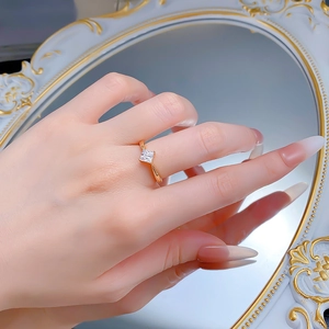 Detail of a gold minimalist ring featuring a square-cut princess diamond on finger