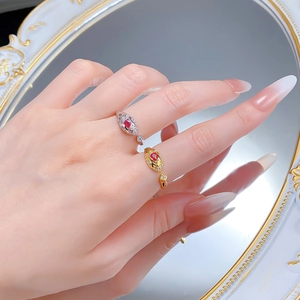 Detail of luxury snake-style open rings in gold and silver with pear-cut ruby stones