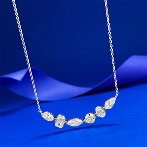 Macro view of S925 silver necklace with various shaped clear gemstones on blue silk