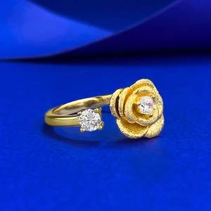 Elegant gold flower ring with sparkling crystals and brushed rose finish on deep blue background