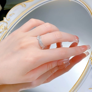 Detailed view of criss-cross leaf ring with brushed texture on hand reflecting in mirror