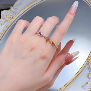 Detail of luxury snake-shaped rings with red teardrop stones on a vintage mirror background