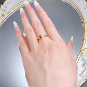Detail of a gold snake ring on a finger featuring a ruby stone and sparkling zircon accents