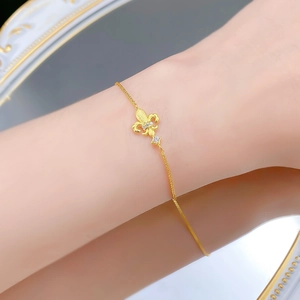 Macro view of gold fleur-de-lis bracelet with brushed finish and micro-set gems