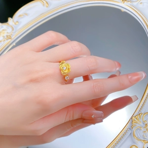 Detail of a brushed gold rose ring with zircon accents on a vintage mirror background