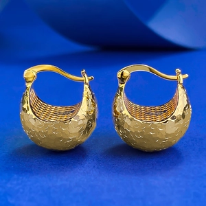 Macro view of gold hoop earrings with hammered texture on a vibrant blue background
